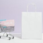 sale sign in a miniature shopping cart and paper bag