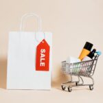 a white paper bag and shopping cart on beige background