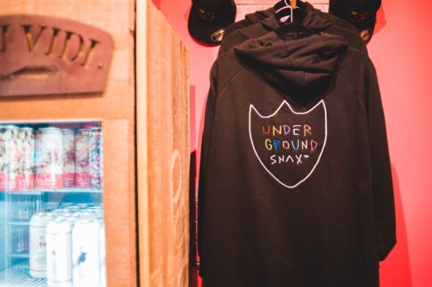 trendy hoodies and fridge with refreshing drinks in shop