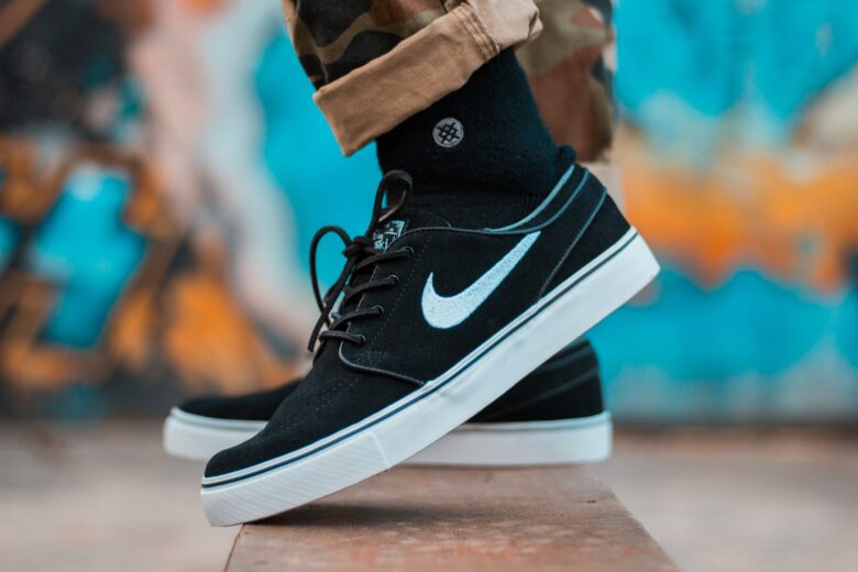 person in brown camouflage pants and black nike sb stefan janoski with black socks