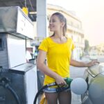 woman in yellow shirt while filling up her car with gasoline